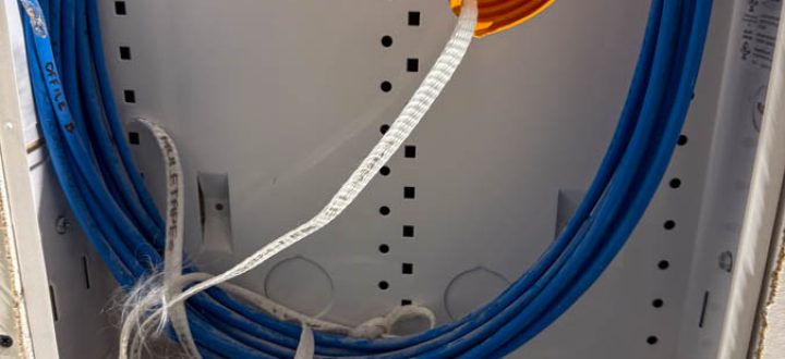 A neatly organized electrical conduit box with blue and orange cables, demonstrating proper cable management techniques.